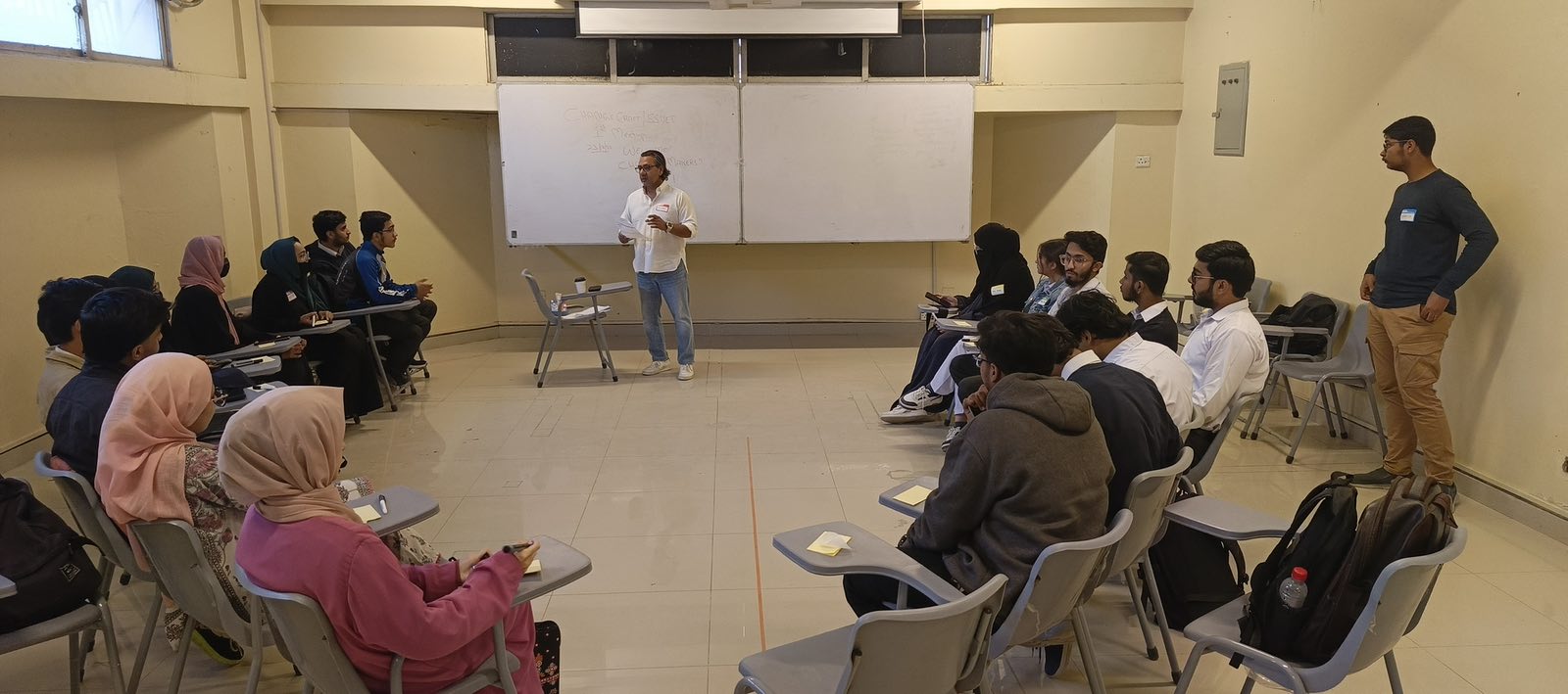 A facilitator speaking to students seated in a classroom at a youth bootcamp in Karachi