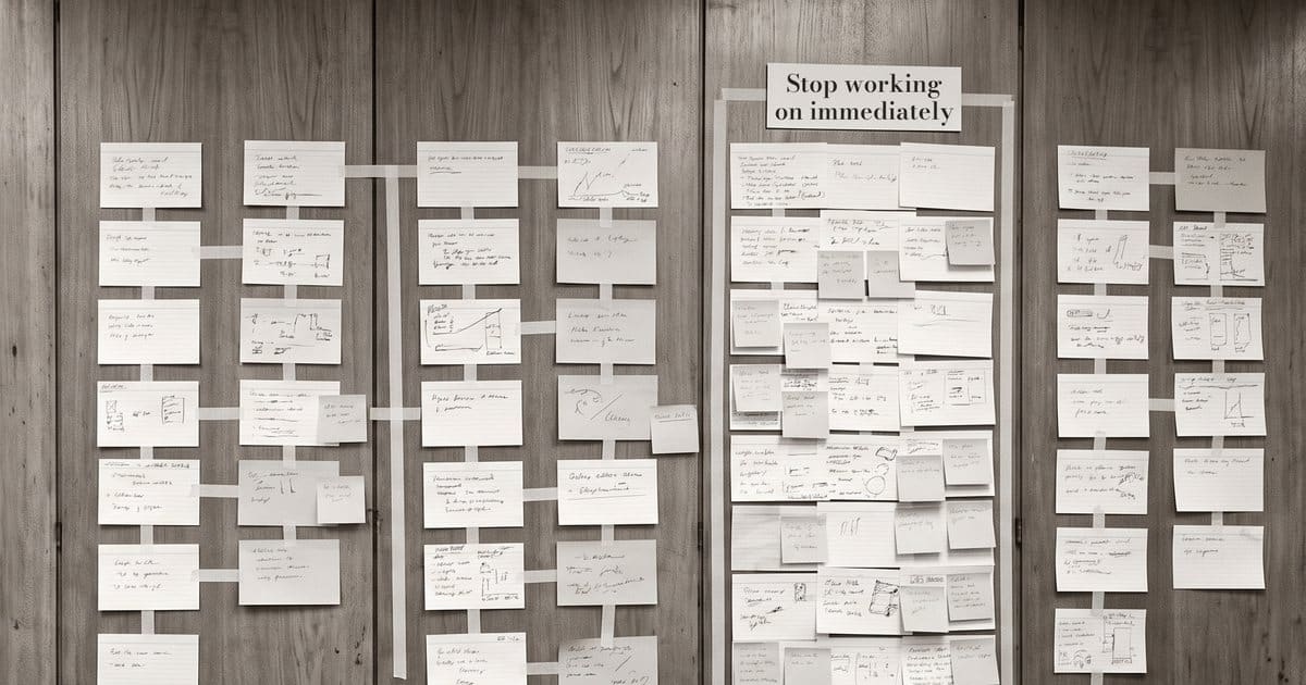 AI redundancies illustration: a wall of index cards in columns, with one taped-off column headed "Stop working on immediately".